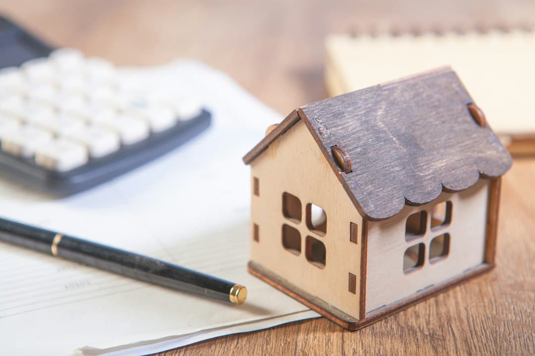A calculator, a pen and a small wooden house model on paperwork, for working out what NEWDYTV IPTV costs